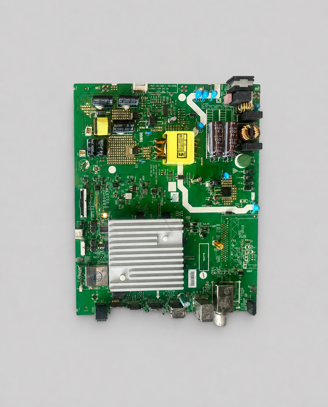 Green TV motherboard PCB with integrated power supply, silver heatsink, capacitors, and connectors isolated on a light gray background.
